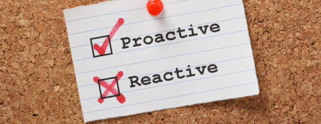 the words proactive and reactive on a index card with a red push pin